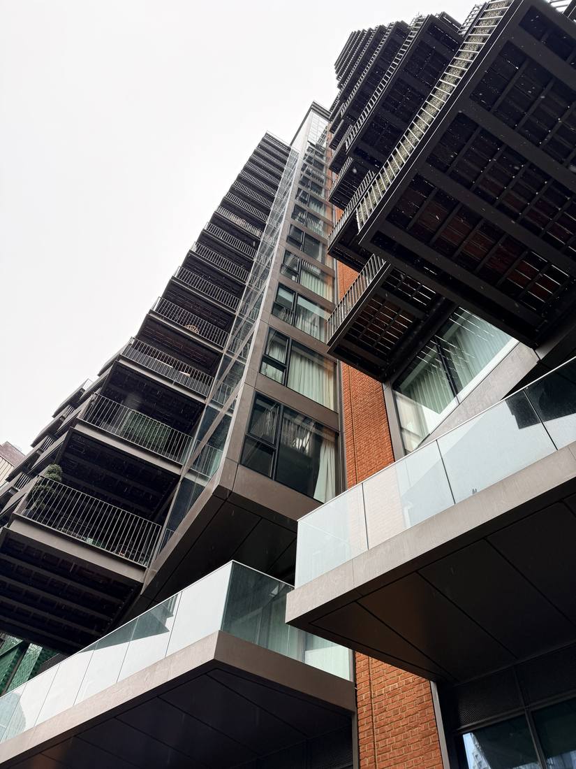 Balconies stacked up a tall building, seen from below