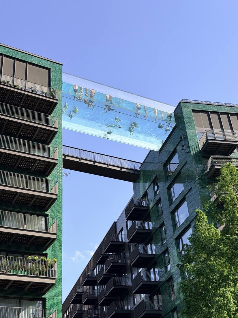 Looking up at the Sky Pool between two green-brick buildings