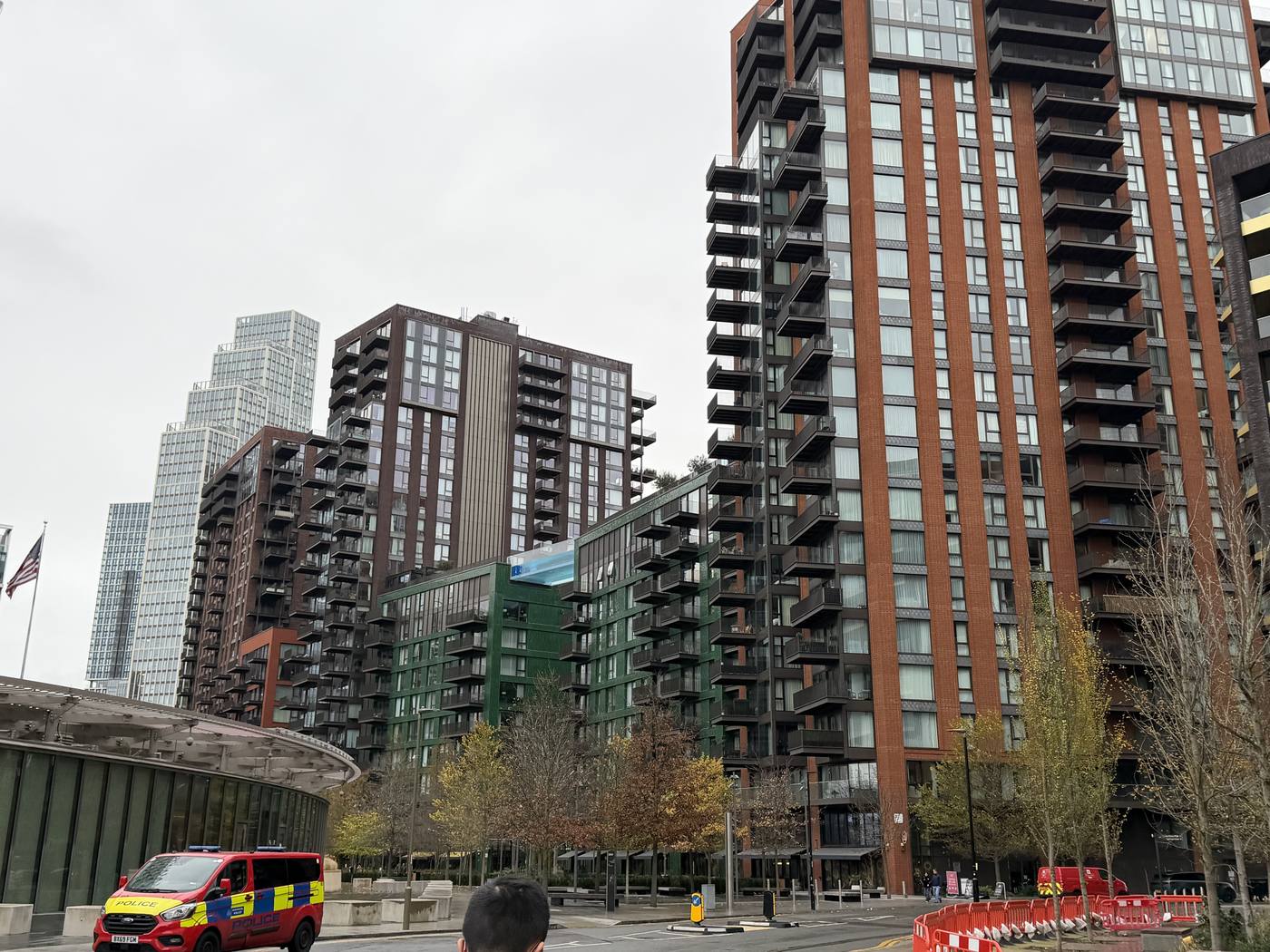 Tall brick apartment buildings and trees along a Nine Elms street