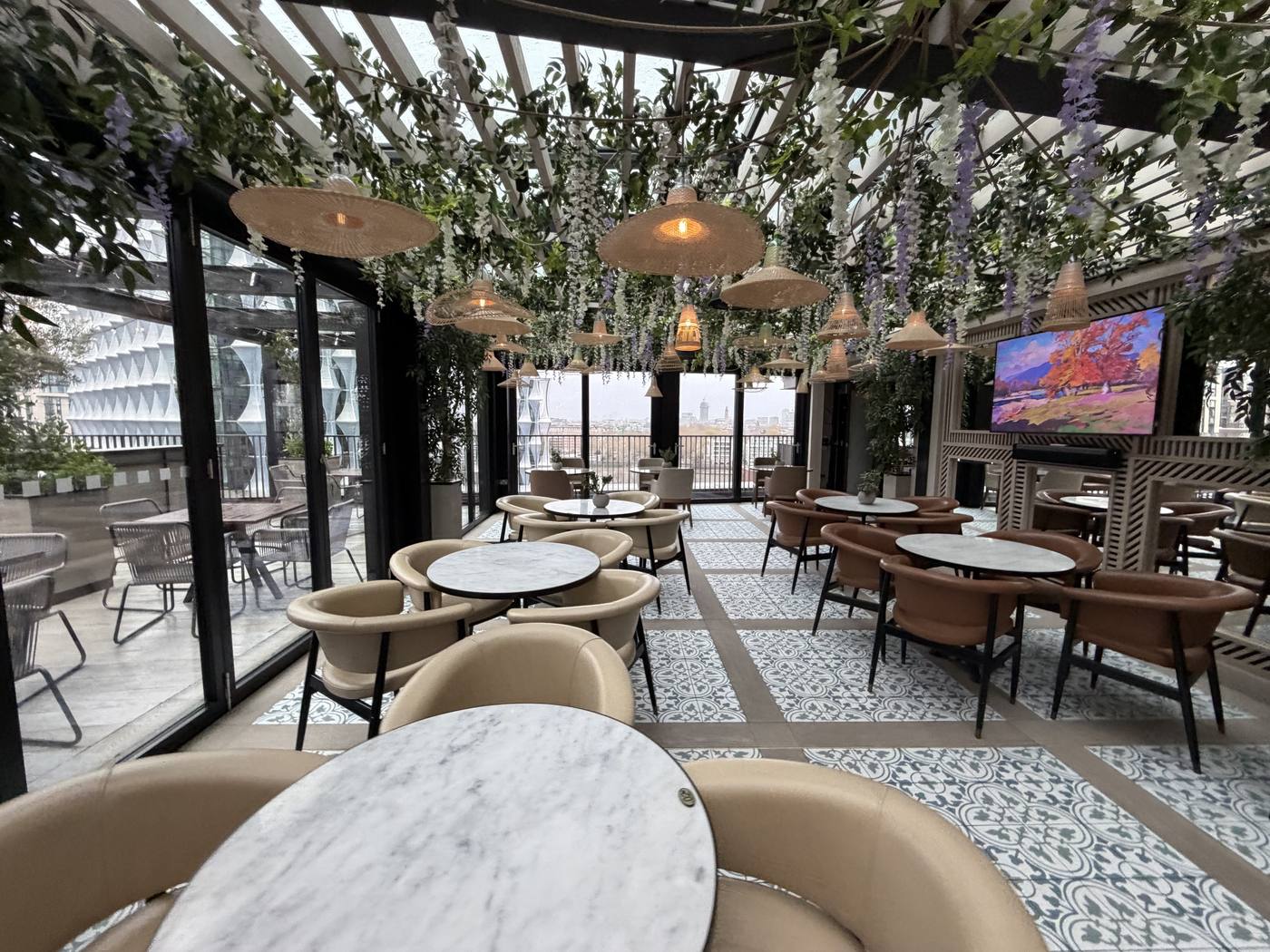 A bright terrace bar with marble tables and wisteria hanging from the ceiling